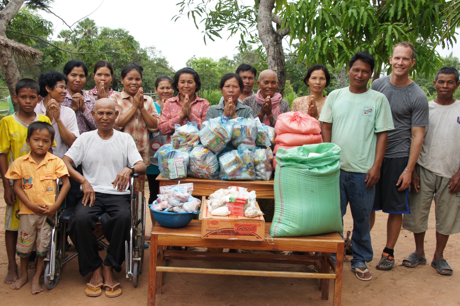 Villagers gathered with thanks around tables of donated food and sacks of rice